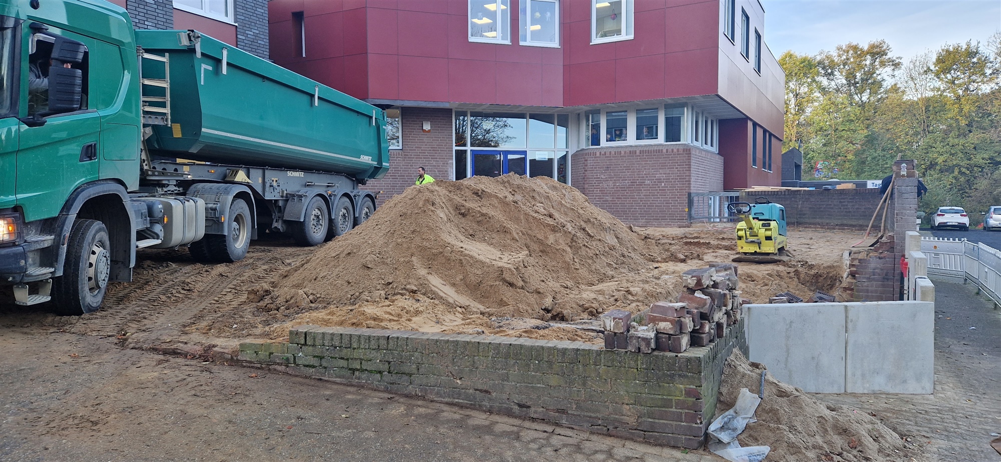 Lkw und Erdarbeiten vor einem Bestandsgebäude