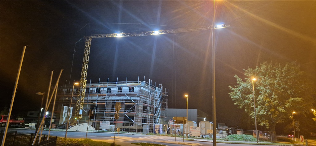 Beleuchtete Baustelle mit Turmdrehkran in der Dämmerung